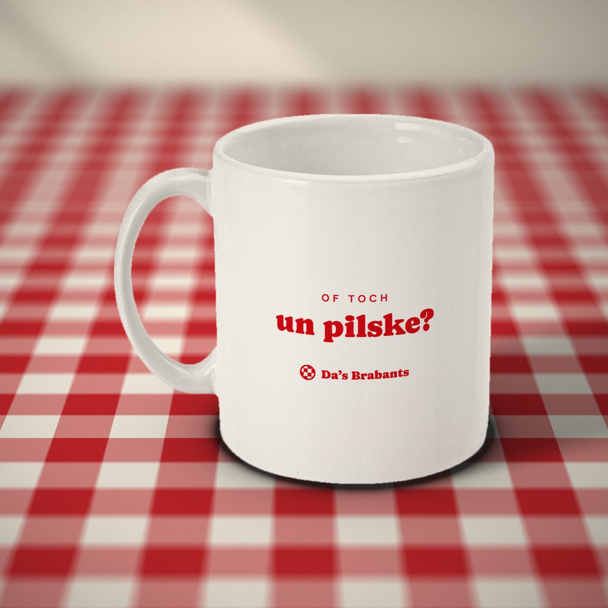 Achterkant: witte mok met in rode letters „of toch un pilske?” en het logo van Da's Brabants