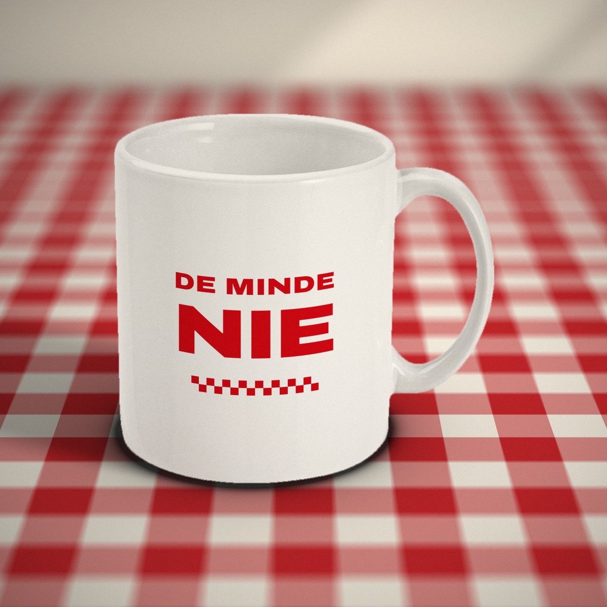 Witte mok met in rode letters de tekst “De minde nie”