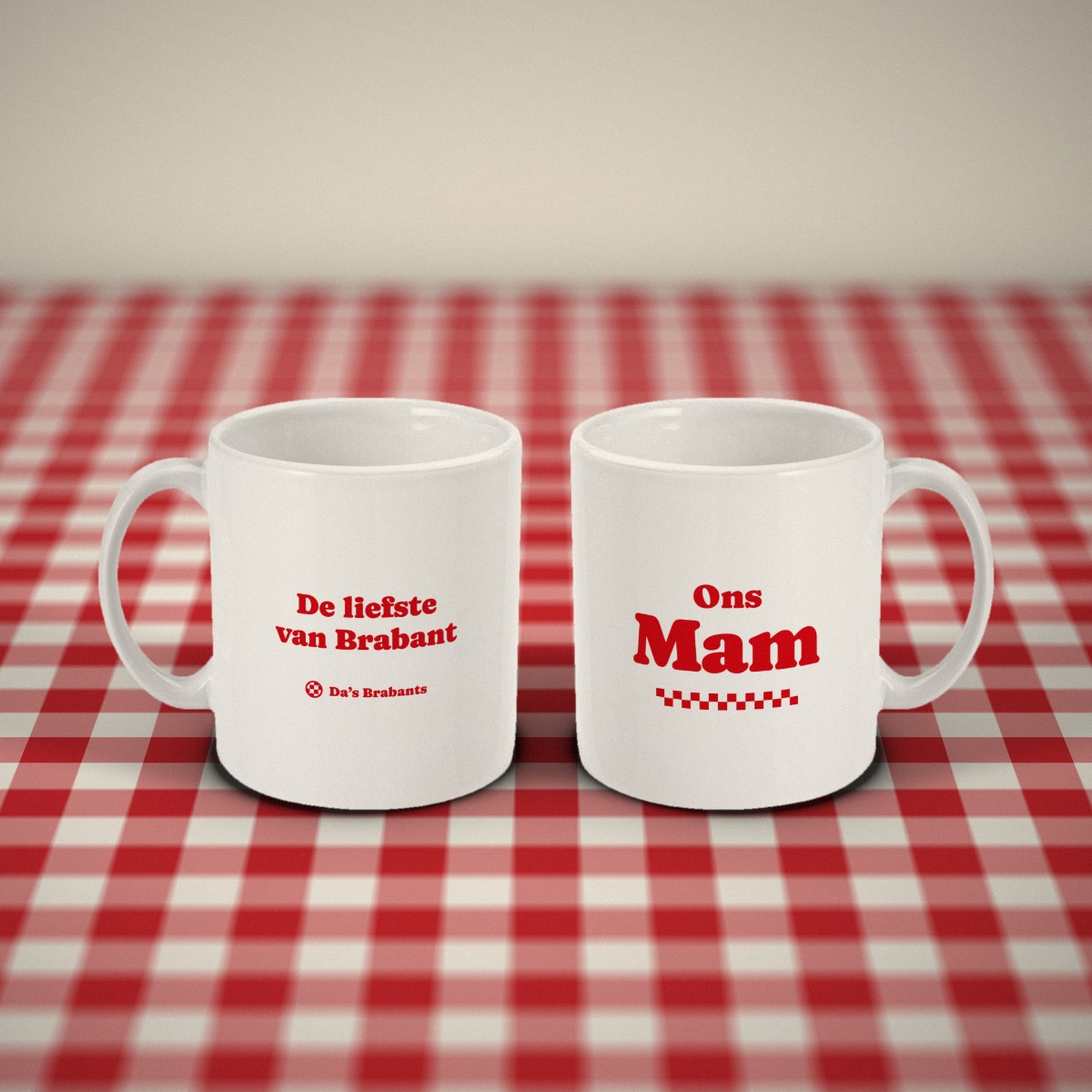 Voor- en achterkant: twee witte mokken „Ons Mam” naast elkaar op een rood-wit geruit tafelkleed